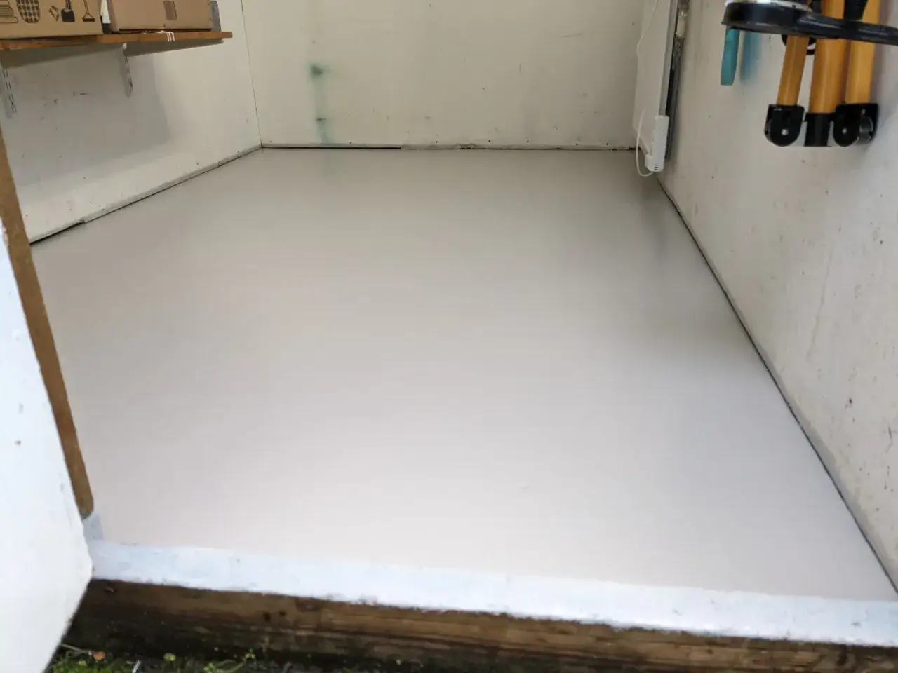 Nyligen målat garagegolv i en ljusgrå nyans. Golvet ser rent och fräscht ut, redo för nya projekt.