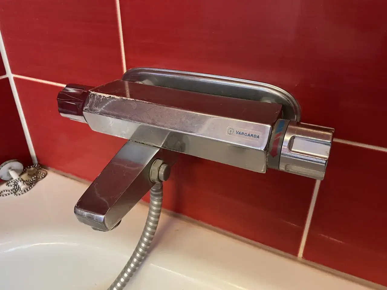 En kromad blandare med Vargårda-märke över ett vitt badkar. En droppande kran kan höras i bakgrunden.