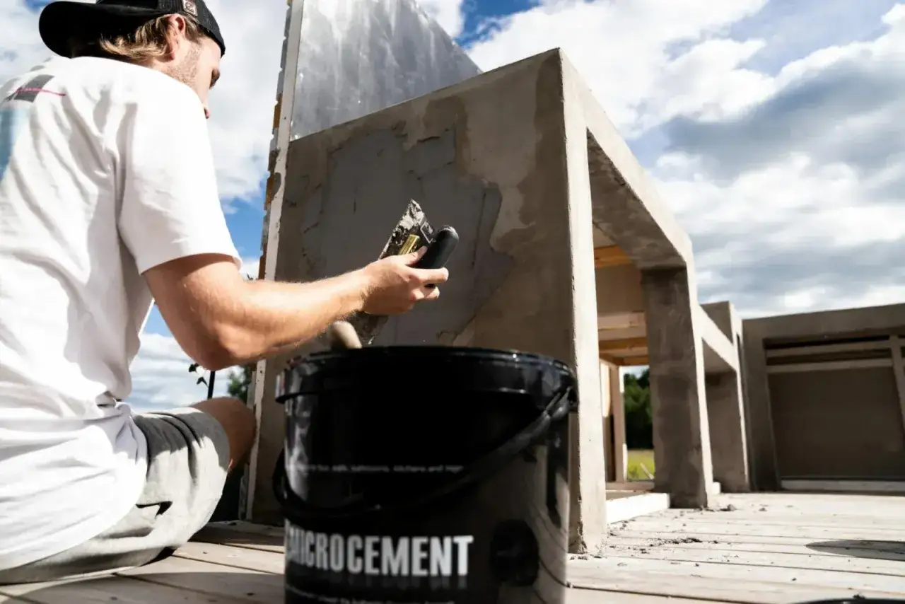 Man applicerar microcement utomhus på en betongkonstruktion. En hink med