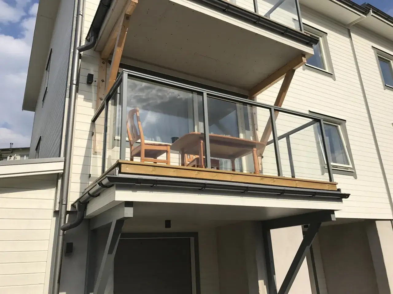 En balkong med bord och stolar, redo för fika. Kanske dyker duvorna på balkongen upp snart för en smula.