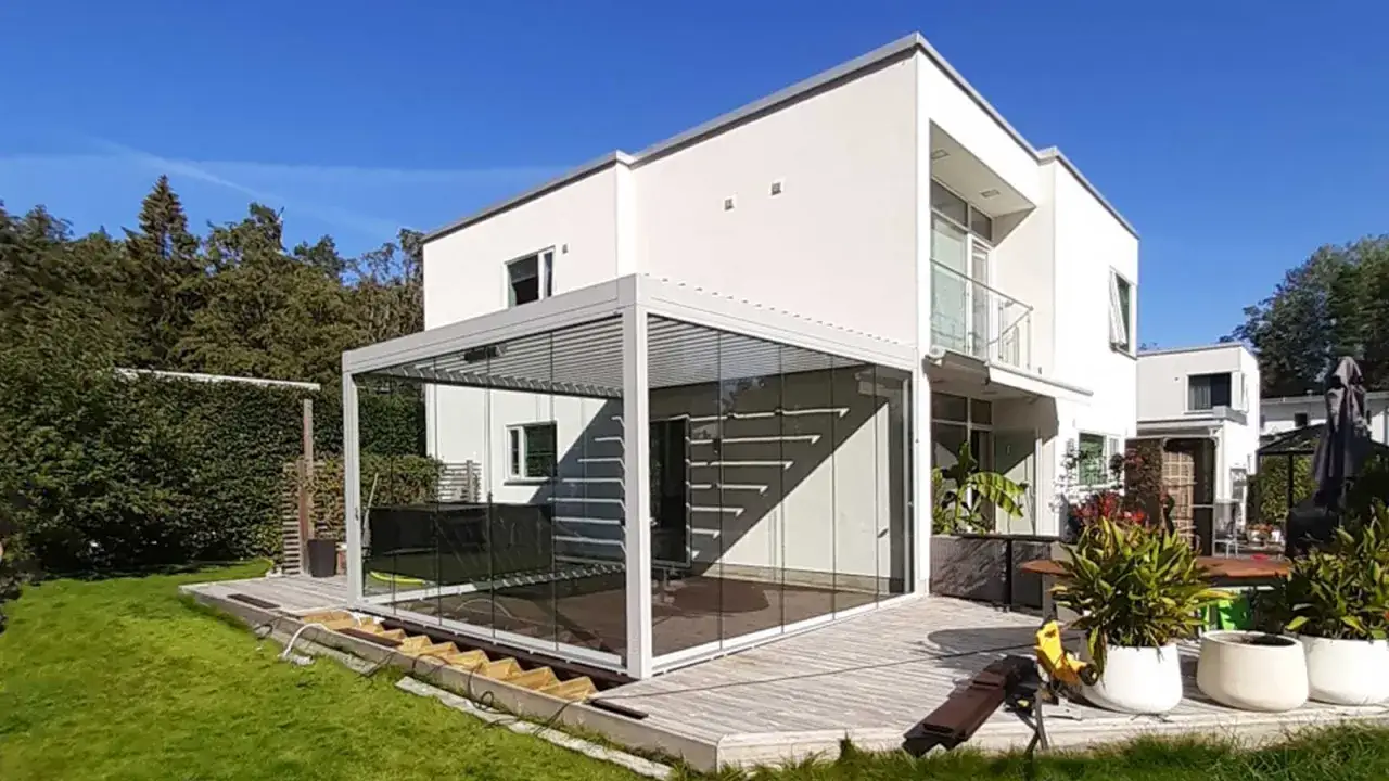 Ett modernt hus med en inglasad altan som ger en härlig utsikt över trädgården. Perfekt för att njuta av sommaren, även om vädret inte är på topp.