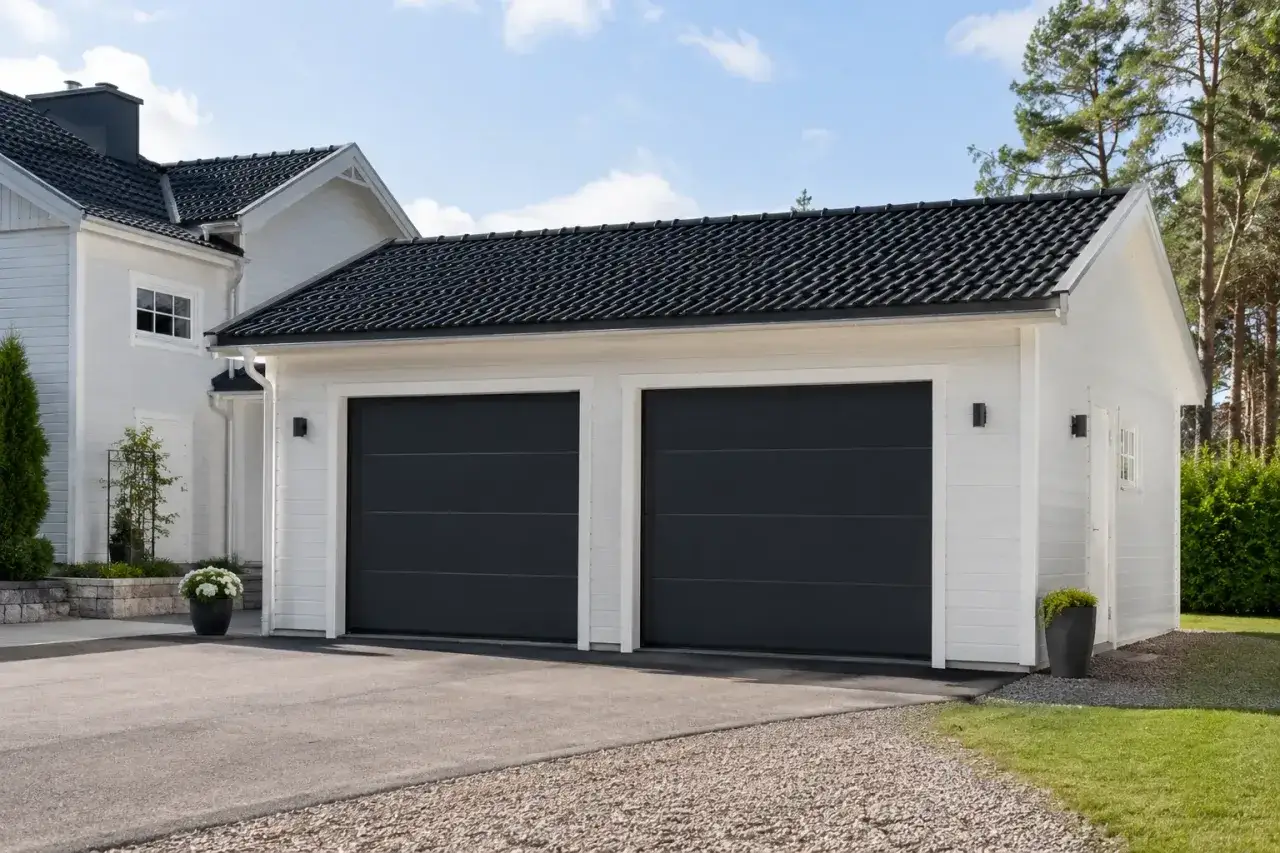 Vitt garage med två mörka portar, perfekt för att bygga garage och förvara bilen tryggt.